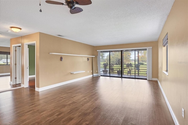 spare room featuring a textured ceiling, plenty of natural light, ceiling fan, and wood-type flooring