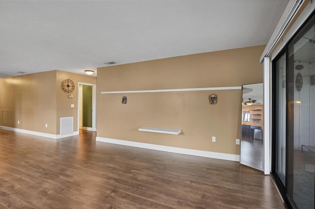 unfurnished room featuring a textured ceiling, ceiling fan, and dark hardwood / wood-style floors