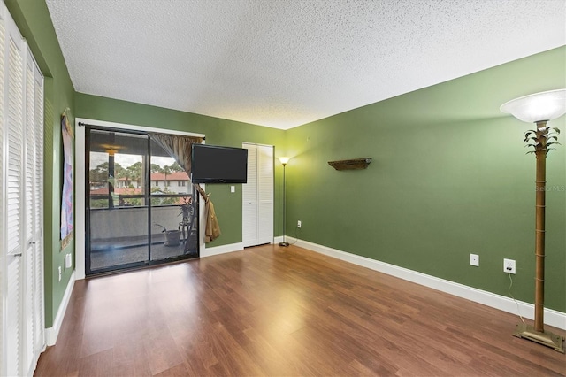 empty room featuring a textured ceiling and dark wood-type flooring