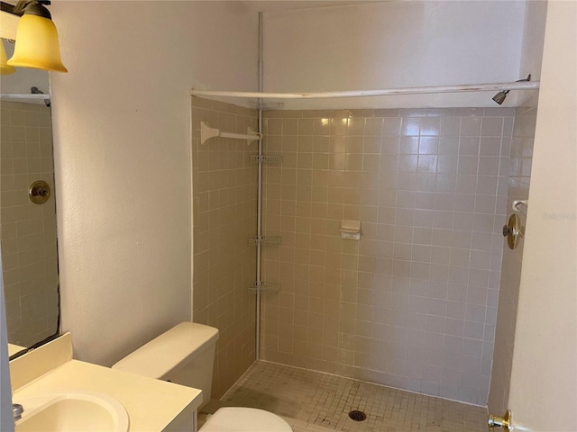 bathroom featuring tiled shower, vanity, and toilet