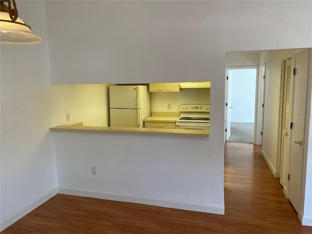 kitchen with dark hardwood / wood-style floors, white appliances, kitchen peninsula, and range hood