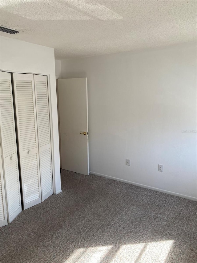 unfurnished bedroom featuring carpet floors, a textured ceiling, and a closet