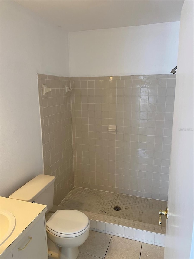 bathroom featuring tile patterned flooring, toilet, a tile shower, and vanity