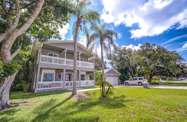 rear view of house featuring a balcony, a garage, a yard, and covered porch