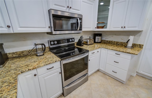 kitchen with stainless steel appliances, light stone countertops, and white cabinets