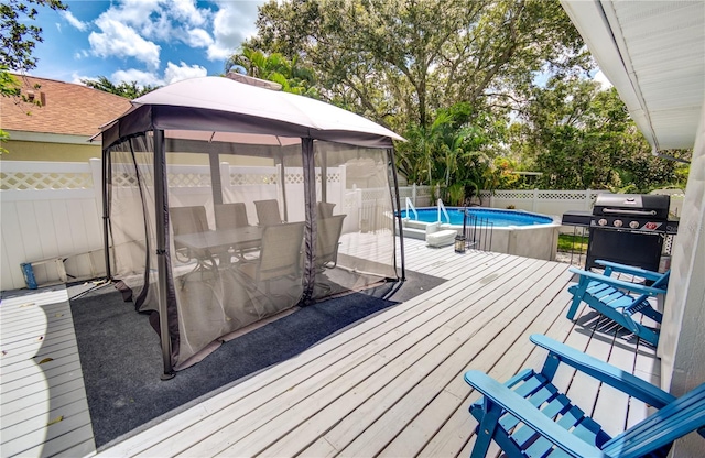 deck featuring a grill, a fenced in pool, and a gazebo