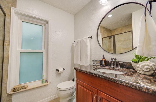 bathroom featuring vanity, toilet, a shower with shower door, and a textured ceiling