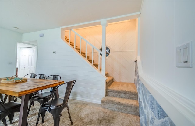 dining area featuring wooden walls and light carpet