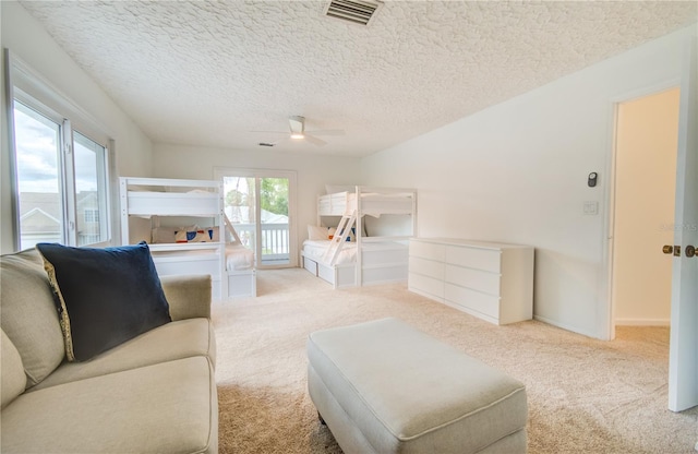 living room featuring a textured ceiling, light colored carpet, and ceiling fan