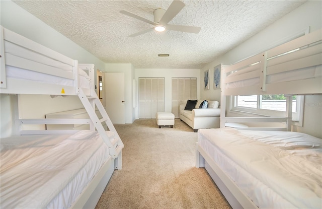 bedroom with a textured ceiling, ceiling fan, and light colored carpet