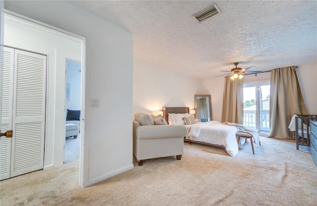 carpeted bedroom with a textured ceiling, ceiling fan, and a closet