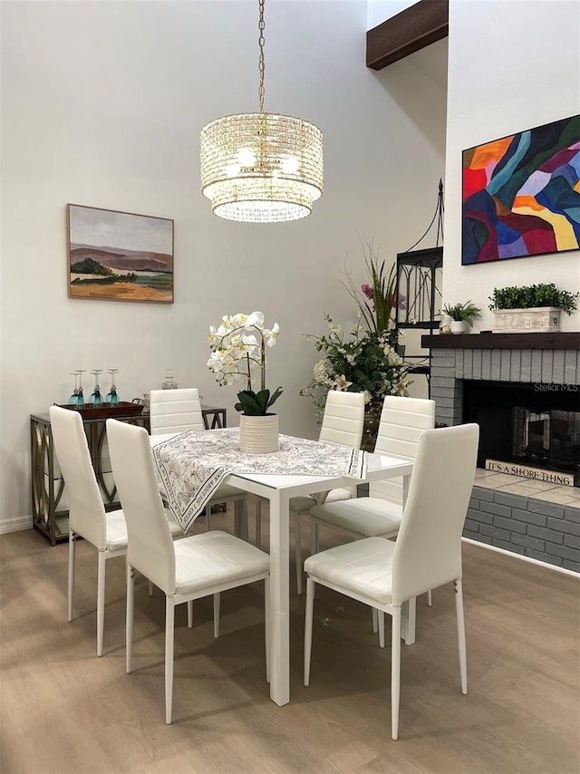 dining space featuring a brick fireplace, hardwood / wood-style flooring, and a chandelier