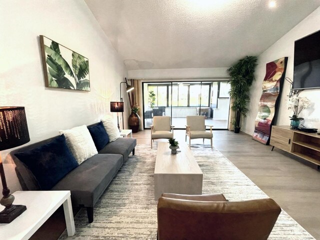 living room featuring vaulted ceiling, a textured ceiling, and hardwood / wood-style floors