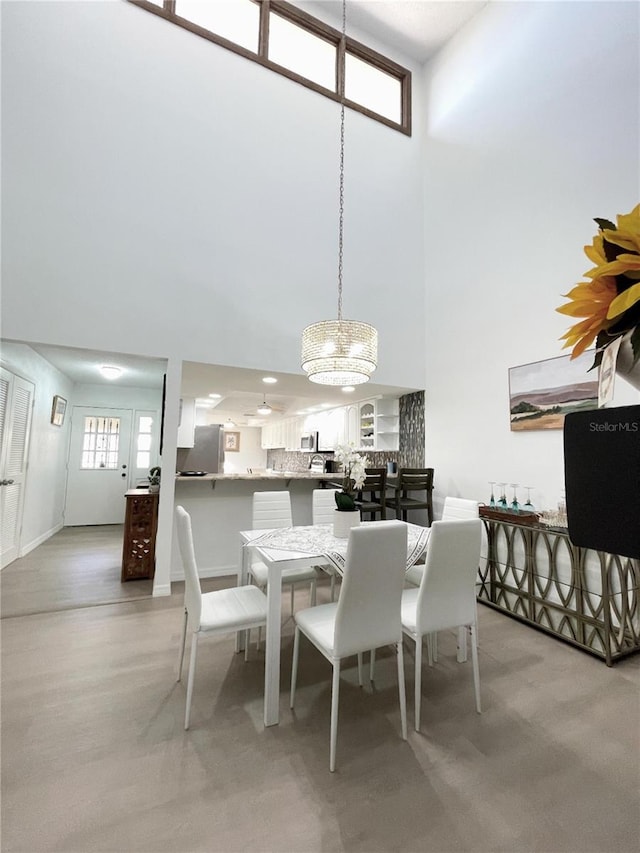 dining area featuring an inviting chandelier and a towering ceiling