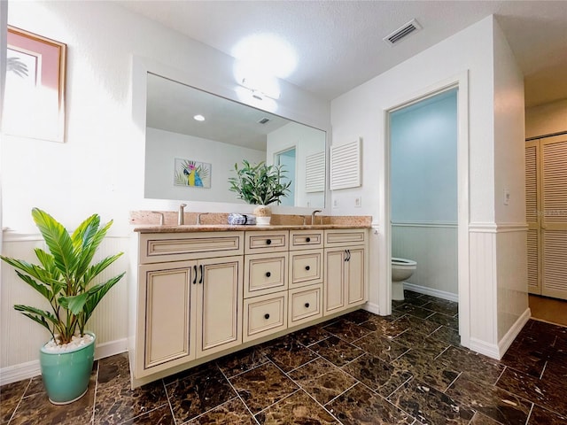 bathroom with a textured ceiling, vanity, and toilet