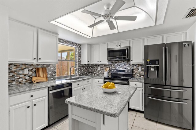 kitchen with appliances with stainless steel finishes, white cabinets, a center island, ceiling fan, and sink