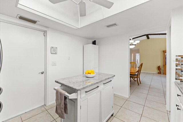 kitchen with ceiling fan with notable chandelier, light tile patterned floors, light stone counters, and white cabinets