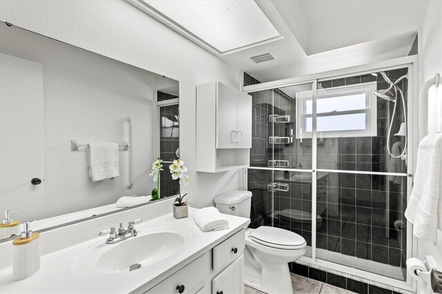 bathroom featuring tile patterned flooring, walk in shower, vanity, and toilet