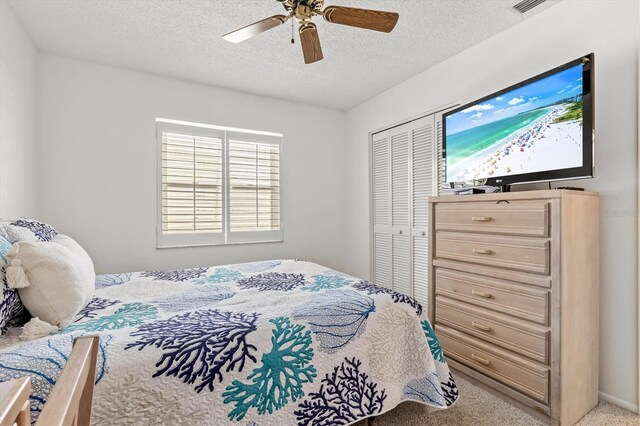 carpeted bedroom featuring ceiling fan, a textured ceiling, and a closet