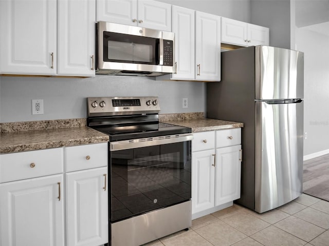 kitchen featuring appliances with stainless steel finishes, light tile patterned floors, and white cabinets