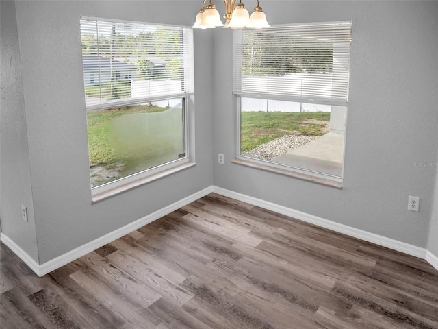 unfurnished dining area with plenty of natural light, wood-type flooring, and a notable chandelier