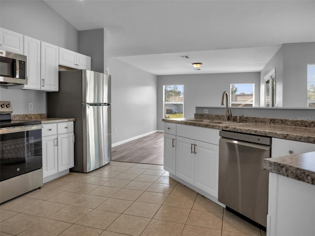 kitchen with white cabinetry, appliances with stainless steel finishes, sink, and light tile patterned floors