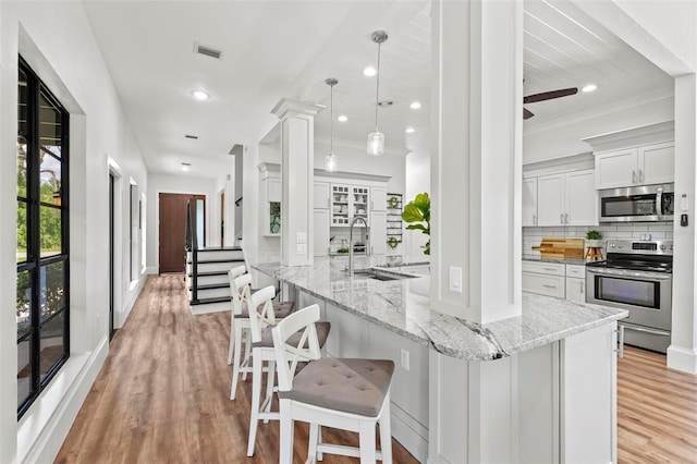 kitchen featuring sink, hanging light fixtures, light stone countertops, white cabinetry, and stainless steel appliances