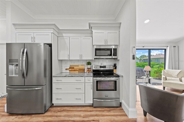 kitchen with decorative backsplash, light stone countertops, light wood-type flooring, appliances with stainless steel finishes, and white cabinetry