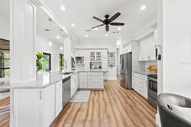 kitchen with kitchen peninsula, white cabinets, decorative light fixtures, and appliances with stainless steel finishes