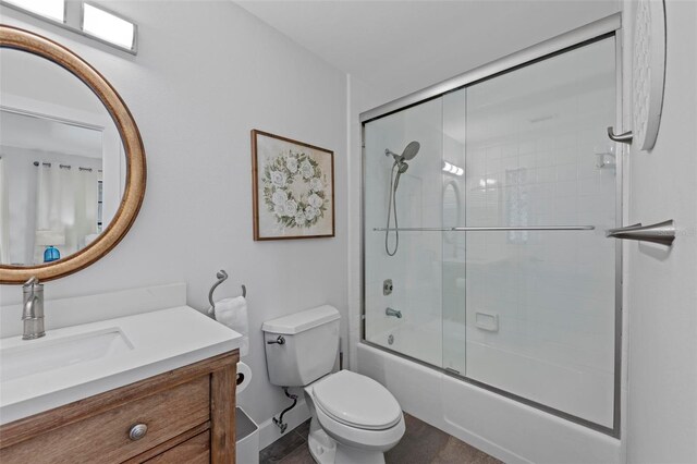 full bathroom featuring vanity, bath / shower combo with glass door, and toilet