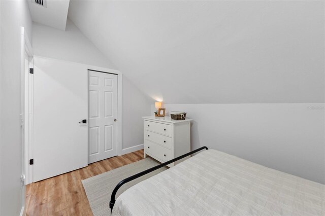 bedroom with light hardwood / wood-style floors, a closet, and vaulted ceiling