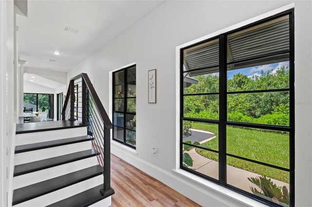 stairs featuring hardwood / wood-style floors and lofted ceiling