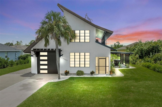 back house at dusk featuring a garage and a yard