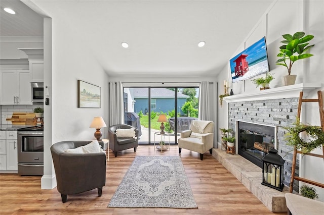 living room with a fireplace, light hardwood / wood-style floors, and vaulted ceiling