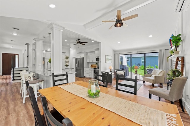 dining space with vaulted ceiling with beams, light hardwood / wood-style floors, ornate columns, and an AC wall unit