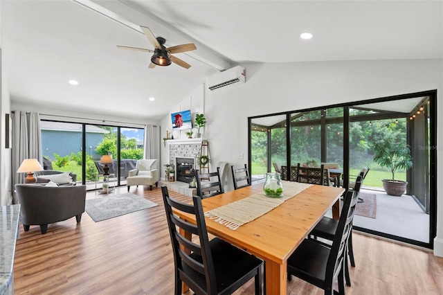 dining space featuring an AC wall unit, ceiling fan, light wood-type flooring, a fireplace, and beam ceiling