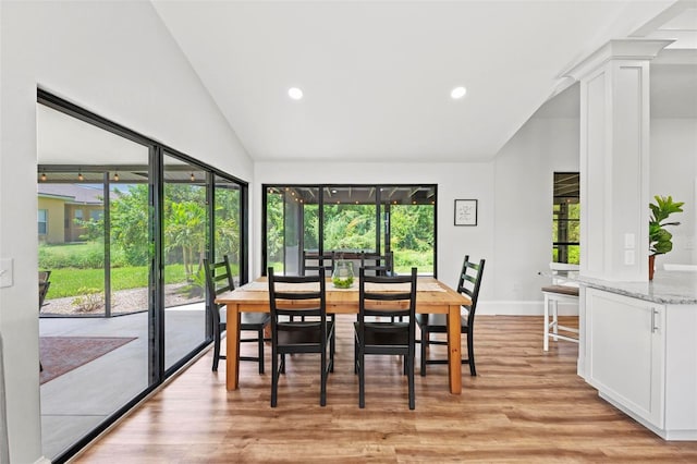 dining room with vaulted ceiling and light hardwood / wood-style flooring