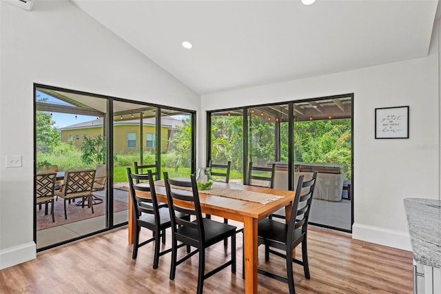 dining area featuring light wood-type flooring and high vaulted ceiling