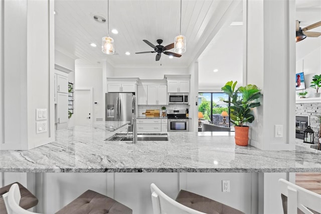 kitchen with appliances with stainless steel finishes, ceiling fan, a peninsula, and a kitchen breakfast bar