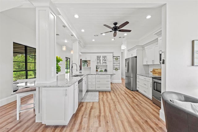 kitchen with a sink, appliances with stainless steel finishes, white cabinets, and a peninsula