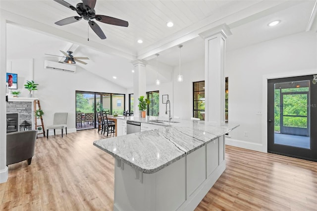 kitchen featuring baseboards, a sink, decorative columns, and a wealth of natural light