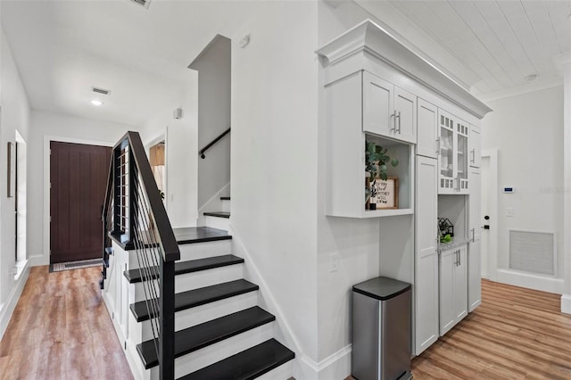 staircase featuring crown molding, baseboards, visible vents, and wood finished floors