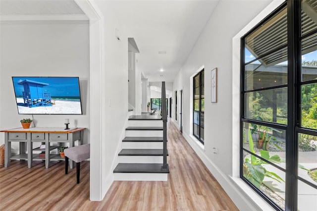 stairway featuring baseboards, a healthy amount of sunlight, and wood finished floors