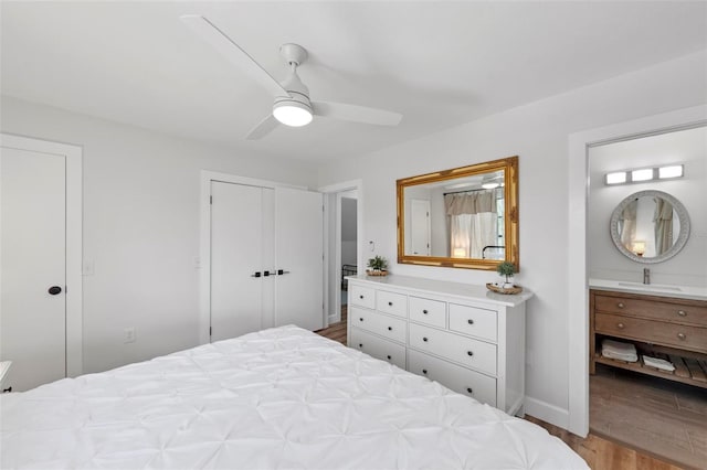 bedroom with ceiling fan, wood finished floors, a sink, baseboards, and ensuite bath