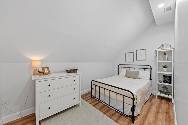 bedroom with light wood-style floors, baseboards, lofted ceiling, and visible vents