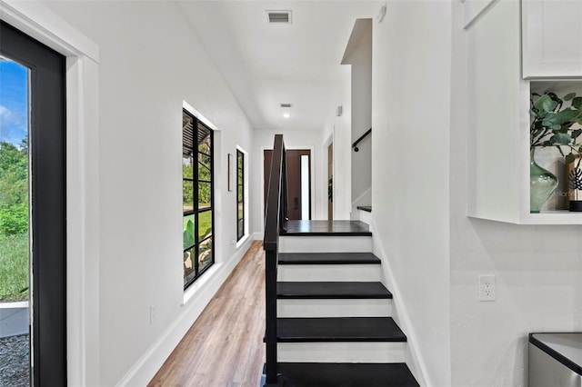 stairs with baseboards, visible vents, and wood finished floors
