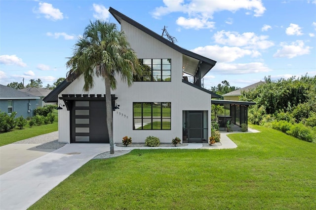 rear view of property with a yard, a sunroom, and concrete driveway