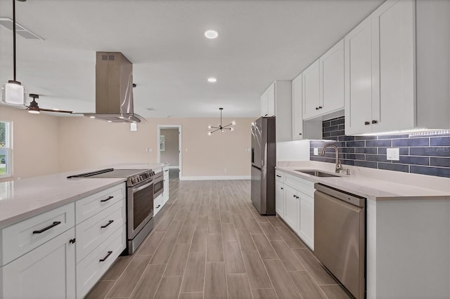 kitchen featuring sink, appliances with stainless steel finishes, wall chimney range hood, and pendant lighting