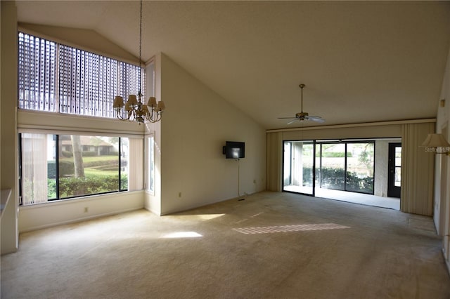 unfurnished living room with ceiling fan with notable chandelier, carpet floors, and high vaulted ceiling