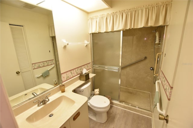 bathroom featuring a shower with door, vanity, wood-type flooring, and toilet